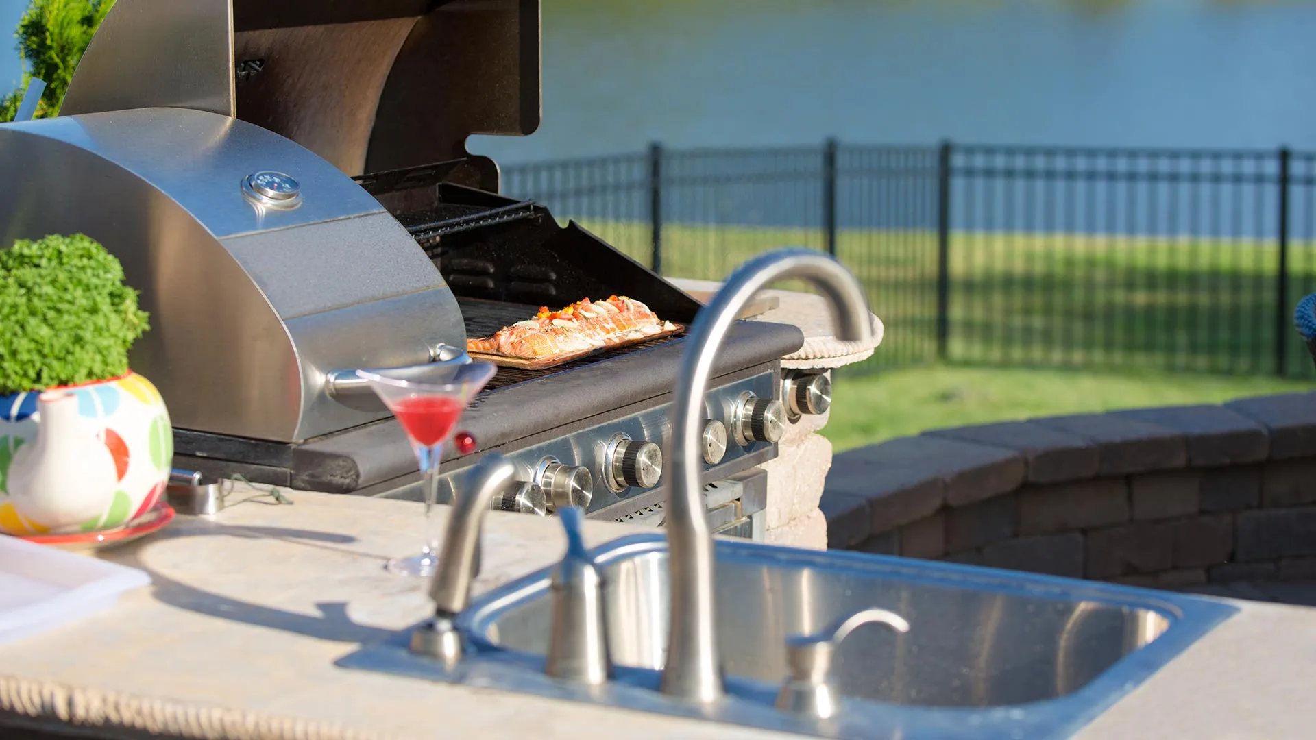 Outdoor kitchen sink and grill on stone counter in Grand Rapids, MI.
