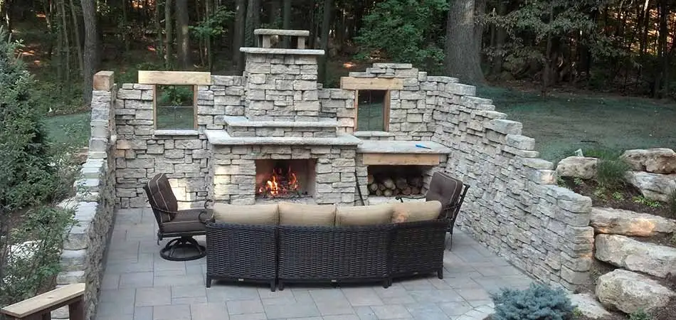 Custom outdoor stone fireplace seating area in Ada, MI.